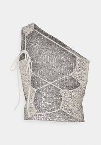 Silver sequined top with asymmetrical design, featuring white trim and adjustable ties. The fabric has a textured, shiny appearance.