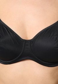 Reggiseno imbottito nero realizzato in tessuto liscio con un design strutturato, dotato di ferretto, spalline regolabili e coppe senza cuciture per un sostegno ottimale.