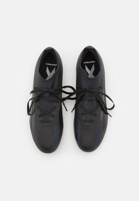 Zwarte sportschoenen met een gestructureerde bovenkant, voorzien van donkerblauwe accenten en platte veters. Ontworpen voor prestatie met een gestroomlijnde vorm.