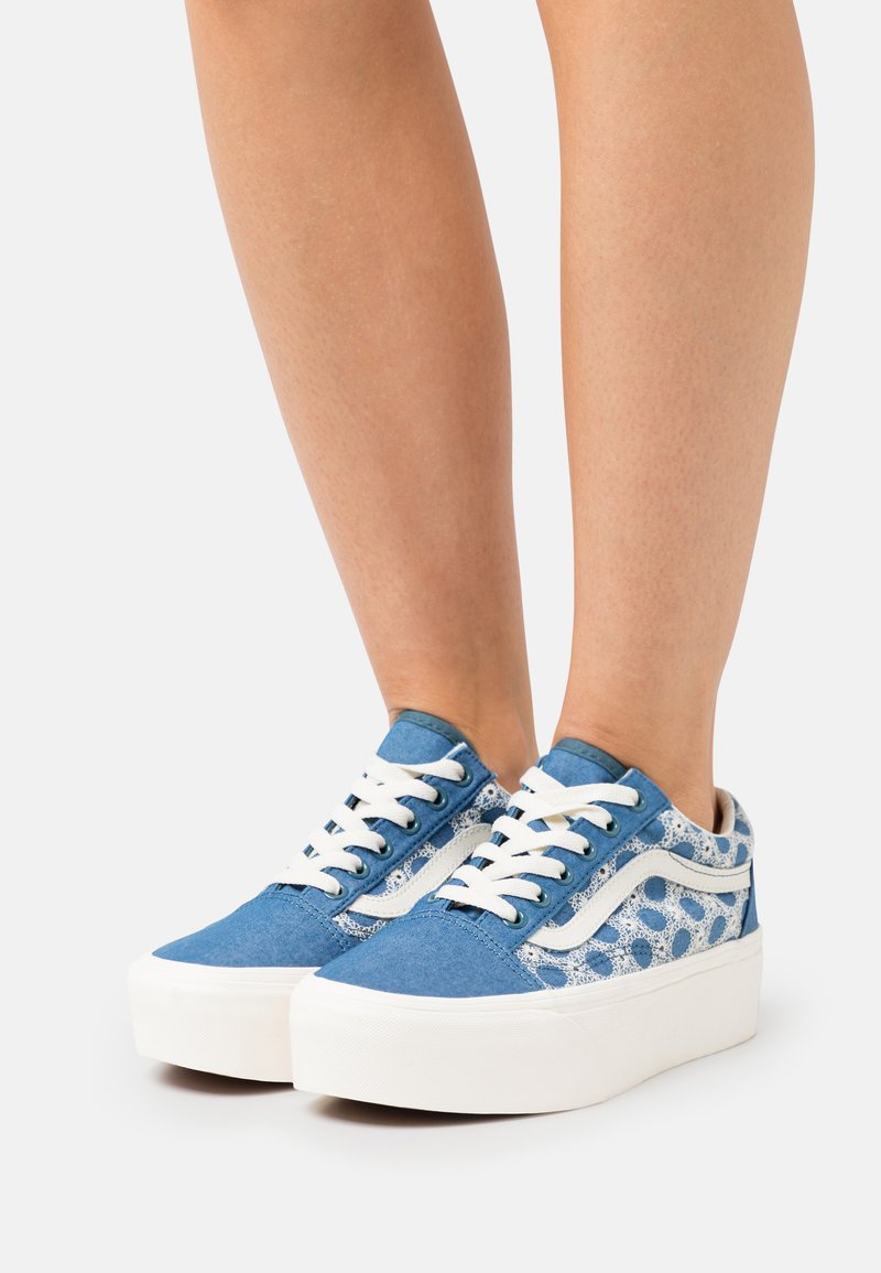 Blue canvas sneakers with white laces and accents, featuring a lace pattern on the sides and a thick, white platform sole.