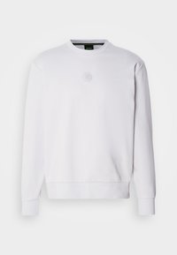 Sweat-shirt blanc à manches longues, simple, avec un petit logo hexagonal sur la poitrine et des poignets côtelés, présenté sur fond blanc.