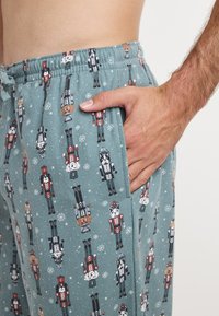 Katoenen pyjamabroek in teal met motieven van notenkrakers en dieren. Ontspannen pasvorm met een elastische tailleband en zijzakken.