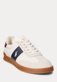 Zapatillas de piel blanca con una franja azul marino y detalles en burdeos, suela de goma, cierre con cordones y un logotipo bordado en el lateral.