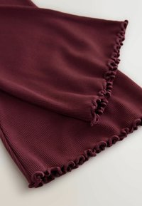 Țesătură ribbed burgundy cu margini ondulate și strânse. Textură moale, design pliat, evidențiind finisajul neted și culoarea constantă.