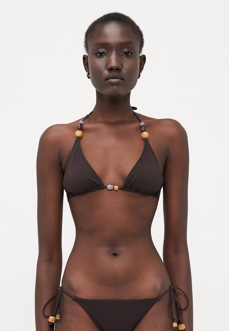 Bruine bikini met driehoekige cups, verstelbare banden en kralenaccenten in geel, paars en oranje. Zachte stof met minimale bedekking.
