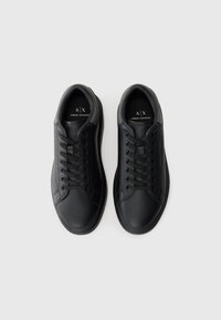 Et par svarte lavsko fra Armani Exchange med snøring, grå kragedetaljer og logo synlig på sålene og siden mot hvit bakgrunn.