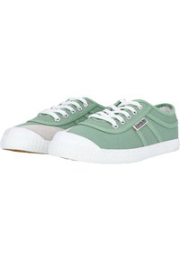 Zapatillas de lona verdes con punteras y suelas de goma blancas. Presentan cordones blancos, ojales plateados y una pequeña etiqueta de la marca en el lateral.