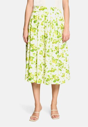 Witte midirok met groene citroen- en bladprint, gedragen met een wit topje en beige sandalen met dunne bandjes en open tenen.