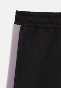 Czarne szorty sportowe z elastycznym pasem i jasnofioletowym paskiem po boku, wykonane z gładkiego, miękkiego materiału.