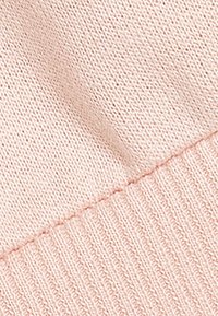 Tejido de punto rosa claro con una textura suave. Presenta un ribete horizontal en el borde, creando un diseño en contraste.