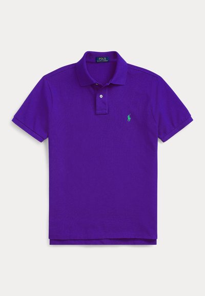 Camisa polo roxa feita de algodão, com colarinho clássico, placket de dois botões e um logotipo verde bordado no lado esquerdo do peito.