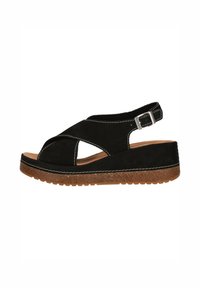Svart mocka sandal med korsremmar och slingback-design. Har en texturerad brun sula och vita sytt accenter.