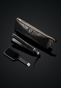 Étui de transport noir à motif crocodile avec fermeture éclair dorée. Comprend un lisseur de cheveux noir élégant et une brosse à cheveux noire texturée.