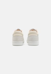 Sneakers con tomaia in camoscio beige e pelle liscia, suola in gomma bianca e colletto imbottito alla caviglia; presentano cuciture a contrasto sul tallone.