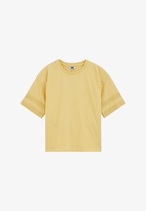 Camiseta amarilla de manga corta con cuello redondo y rayas horizontales texturizadas cerca de los extremos de las mangas, exhibida sobre un fondo blanco.