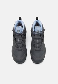 Chaussures de randonnée noires avec dessus en mesh et caoutchouc, surface texturée et accents bleus. Dotées d'un système de laçage et d'un col rembourré pour plus de confort.