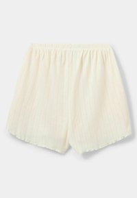 Fehér, felhúzható sort, textúrált, függőleges csík mintával, behúzott derékkal és enyhén díszített szegéllyel.