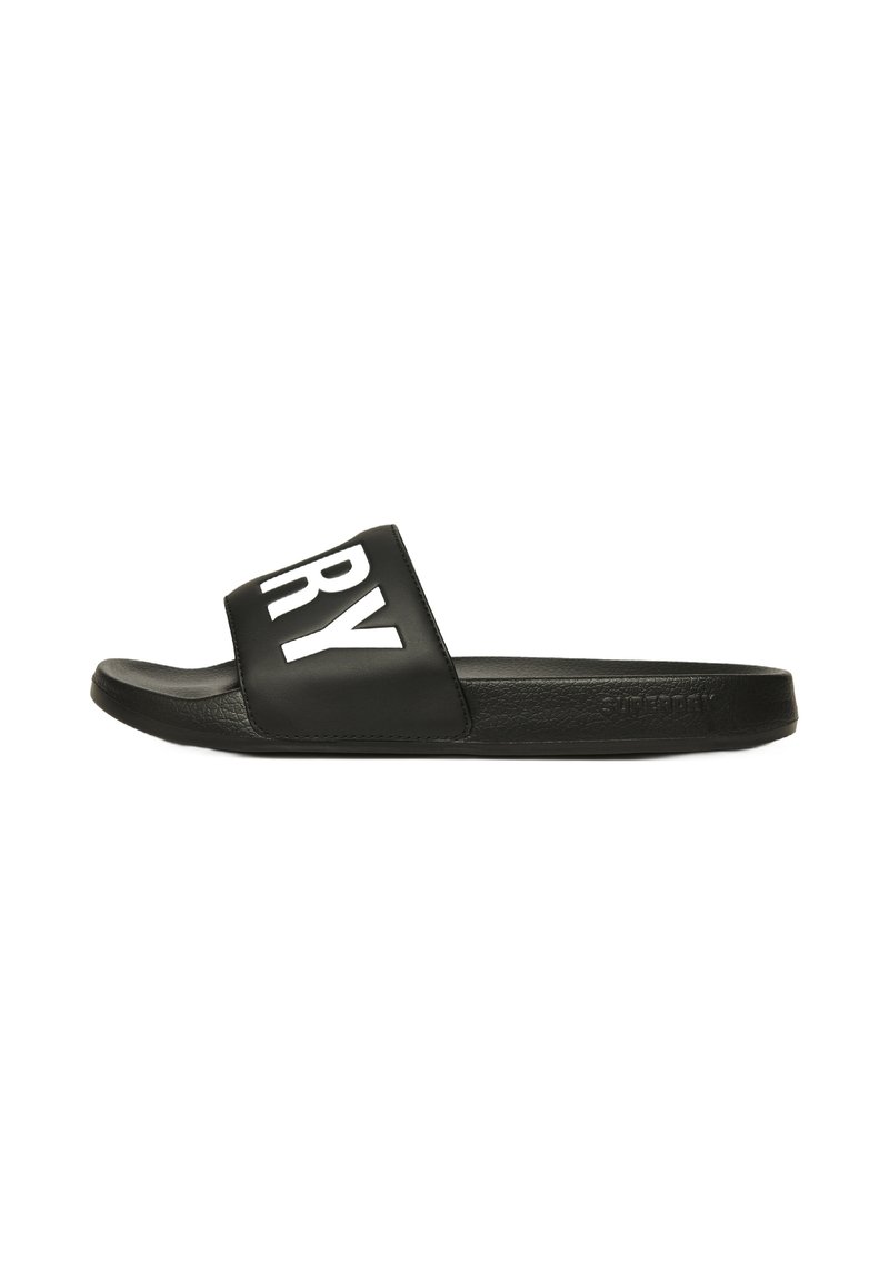 Zwarte slide sandalen met een brede band, met witte blokletters die "DRY" spellen. Gladde textuur met een platte rubberen zool.