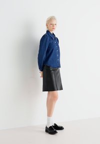 Džinsinis marškinėliai su ilgomis rankovėmis, дерžfrom black leather skirt, ankle-length white socks, and black loafers.