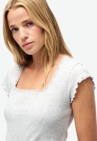 Camiseta de rayas en gris claro con escote cuadrado y ribete de encaje. Presenta mangas cortas con volantes y una textura suave.