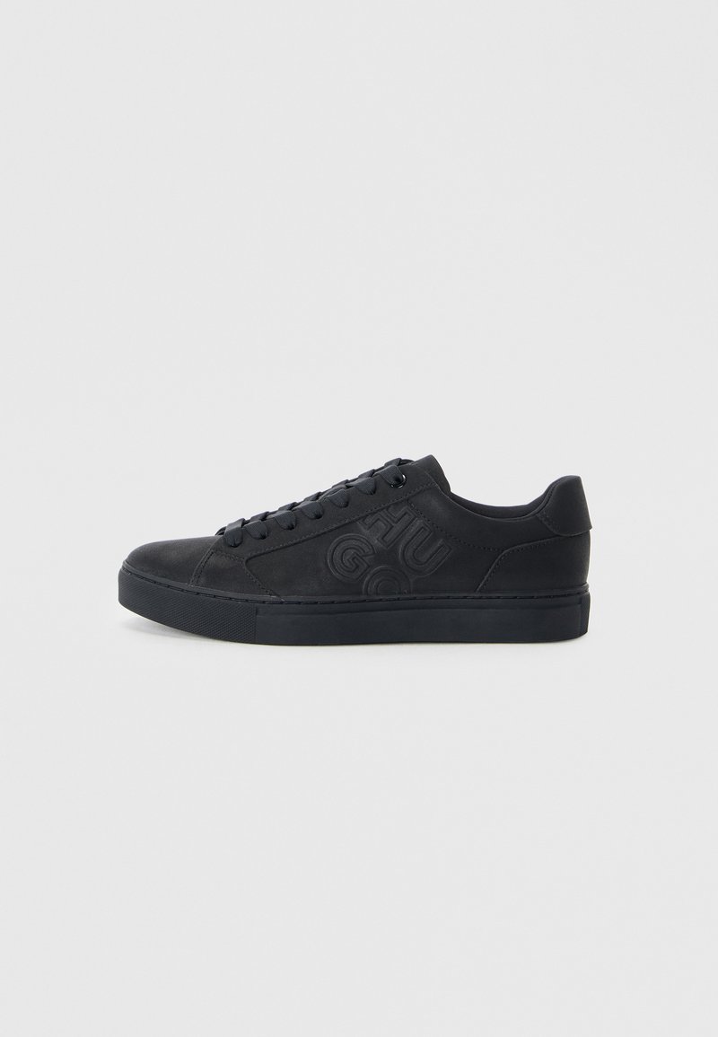 Black sneakers with a smooth leather-like surface, round toe, flat rubber sole, and embossed logo detail on the side. Lace-up design.
