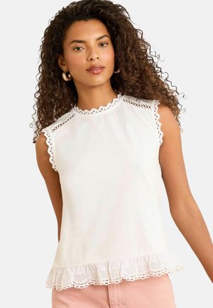 Haut sans manches blanc avec un décolleté en feston et une dentelle au niveau de l'ourlet. Fabriqué en tissu léger, avec des détails en œillets sur les épaules.