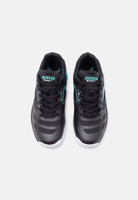 Ζεύγος μαύρων και τιρκουάζ αθλητικών παπουτσιών Joma με κορδόνια, πλέγματα και λευκές σόλες, από πάνω σε λευκό φόντο.