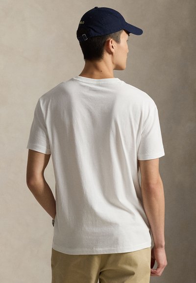 White cotton T-shirt with a classic crew neck and short sleeves, paired with a navy cap featuring the text "POLO" on the back.