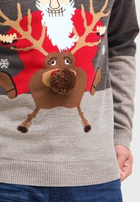 Strick-Weihnachtspullover mit einem Rentier- und Weihnachtsmann-Motiv in Rot, Braun und Grau, mit einer flauschigen braunen Pompon-Nase und strickartiger Textur.