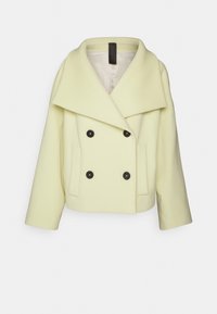 Krémový dvouřadý vlněný blejzr s širokými klopami, čtyřmi černými knoflíky, dlouhými rukávy a dvěma předními kapsami.