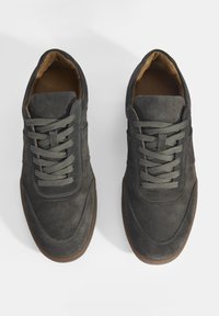 Gray suede sneakers featuring a rounded toe, textured laces, and a tan lining. The rubber sole provides traction and durability.