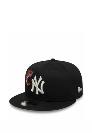 Black snapback cap with white NY logo front and red fish graphic on the left side, featuring a flat brim and New Era logo on the right side.