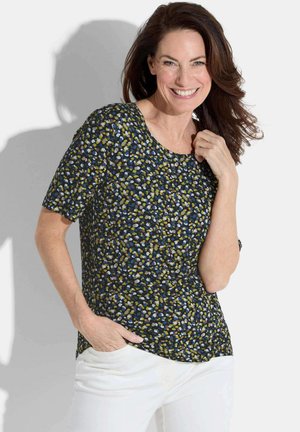 Haut à manches courtes bleu marine avec un motif moucheté en bleu, vert et blanc, col rond et coupe décontractée. Associé à un pantalon blanc.