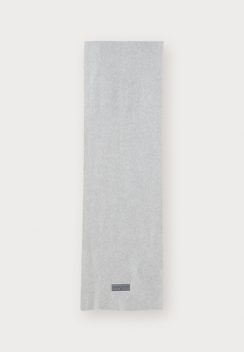 Light gray ribbed scarf made of soft fabric, featuring a rectangular shape and a small branded label near the bottom edge.