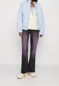 Quiltad ljusblå bomberjacka, krämfärgad button-up topp, mörka utsvängda jeans med ombre-effekt, och tjocka krämfärgade platåskor.