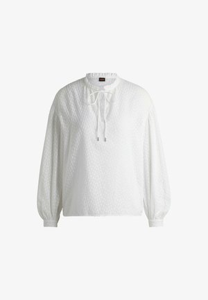 Blusa bianca a maniche lunghe con un motivo testurizzato, scollatura rotonda e chiusura a cravatta sul davanti; polsini elasticizzati e vestibilità rilassata.