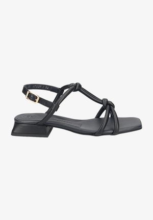 Black sandal featuring multiple knotted straps, flat sole, and a low block heel. Material appears smooth with minimal detailing.