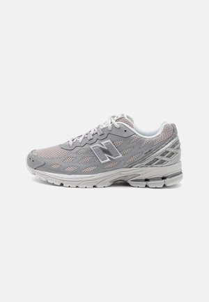 Chaussure de running New Balance gris clair avec tige en mesh, semelle épaisse et amortie, et détails réfléchissants sur fond blanc.