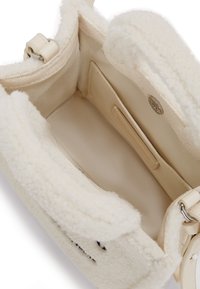 Shearling handbag in cream with smooth leather accents; interior features a fabric lining, a storage pocket, and a silver-tone snap closure.