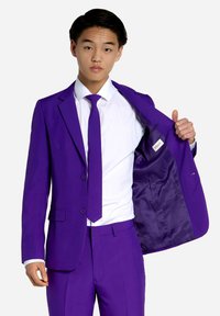 Ljubičasti odijelo slim fit kroja, s dva gumba, teksturiranom tkaninom i unutarnjim džepom, upareno s bijelom košuljom i odgovarajućom kravatom.