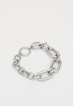 Bracelet en chaîne en argent, présentant des maillons ovales et rectangulaires entrelacés avec un fermoir à bascule et un attachement de charme circulaire. Texture lisse.