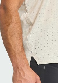 Ανοιχτό μπεζ κοντομάνικο πουκάμισο με μικρές μαύρες τρυπούλες, διαθέτει πλαϊνή σχισμή και λεπτομέρεια λογότυπου. Μαλακό ύφασμα με άνετη εφαρμογή.