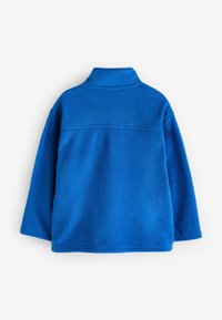 Giacca in pile blu con colletto rialzato, maniche lunghe e texture uniforme. Presenta dettagli delle cuciture superiori sulla schiena.