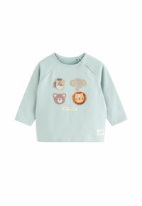 Jasnoniebieska bluza z raglanowymi rękawami i czterema naszywkami ze zwierzętami: lwem, słoniem, niedźwiedziem i żyrafą. Posiada naszywkę "przyjaciele z safari".