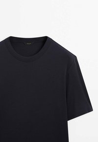 T-shirt nera a maniche corte in cotone con scollatura rotonda, esposta su uno sfondo bianco.