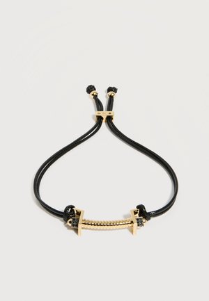 Bracelet à cordon réglable noir avec un centre en spirale dorée et de petits accents de pierres précieuses noires à chaque extrémité.