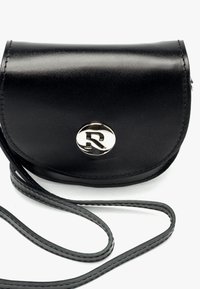 Sac bandoulière en cuir noir au design incurvé, avec une fermeture à bouton-pression et un logo circulaire argenté. Il comporte une fine sangle d'épaule.