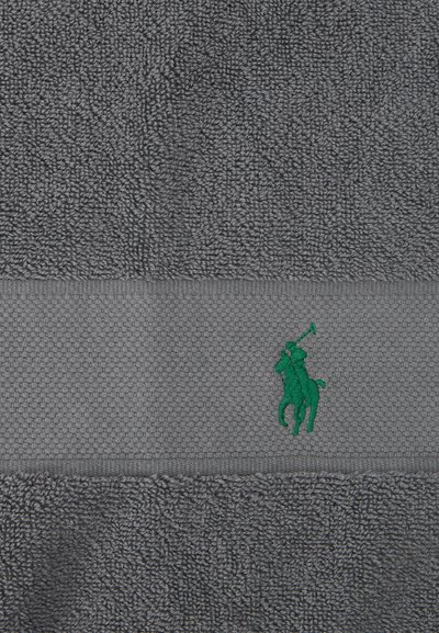 Γκρι πετσέτα με υφή και λωρίδα που φέρει κεντημένο πράσινο παίκτη πόλο επάνω σε άλογο που κρατά ένα μαλέτι.