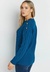 Blauer Strickpullover mit strukturiertem Muster, runder Ausschnitt und dekorativen goldenen Knöpfen an der Schulter. Weiches, dickes Material.