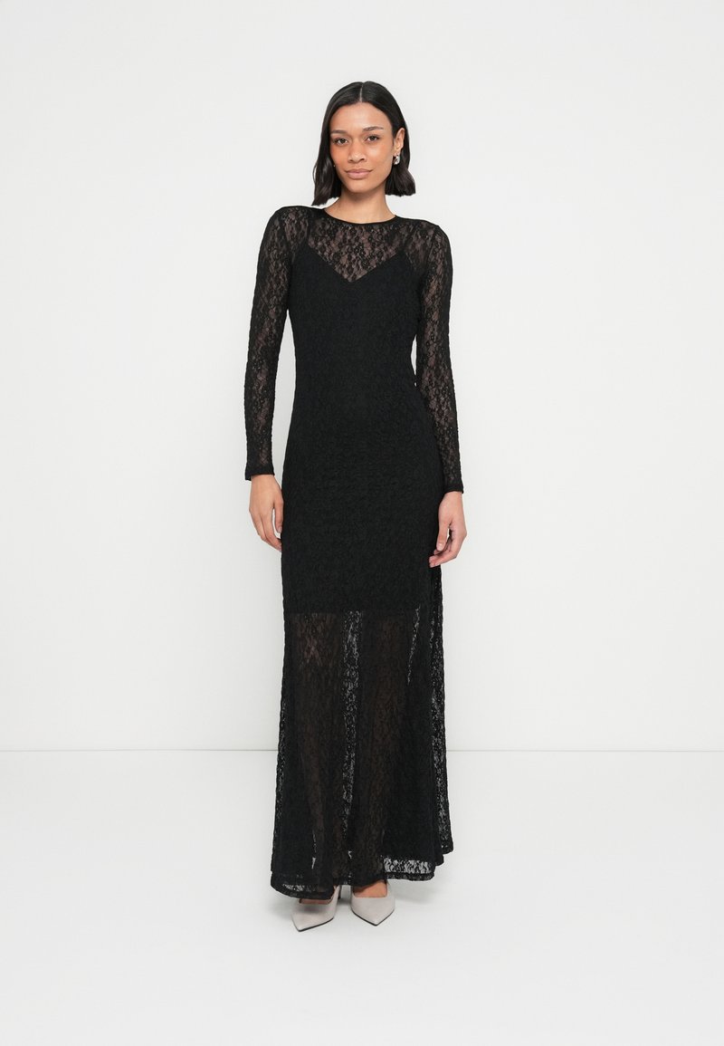 Črna čipkasta obleka z dolgimi rokavi, ki ima oprijetim korzet, tekočo krilo in prozorno spodnjo polovico. Gladek tekstura z izrazito izrezom.